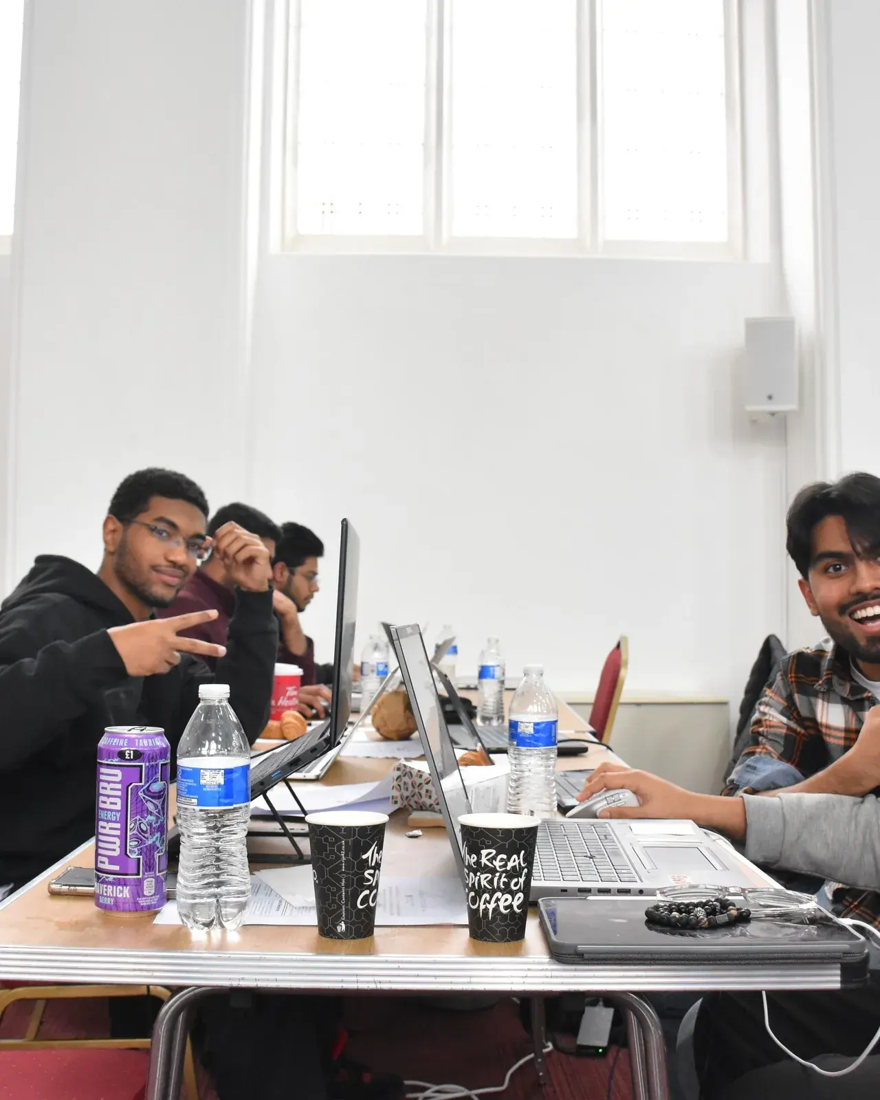 Hackathon participants smiling and giving thumbs up at their table