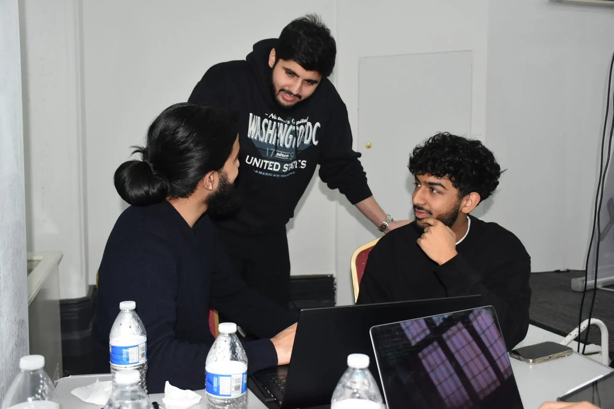 A mentor leaning in to help a team during the hackathon