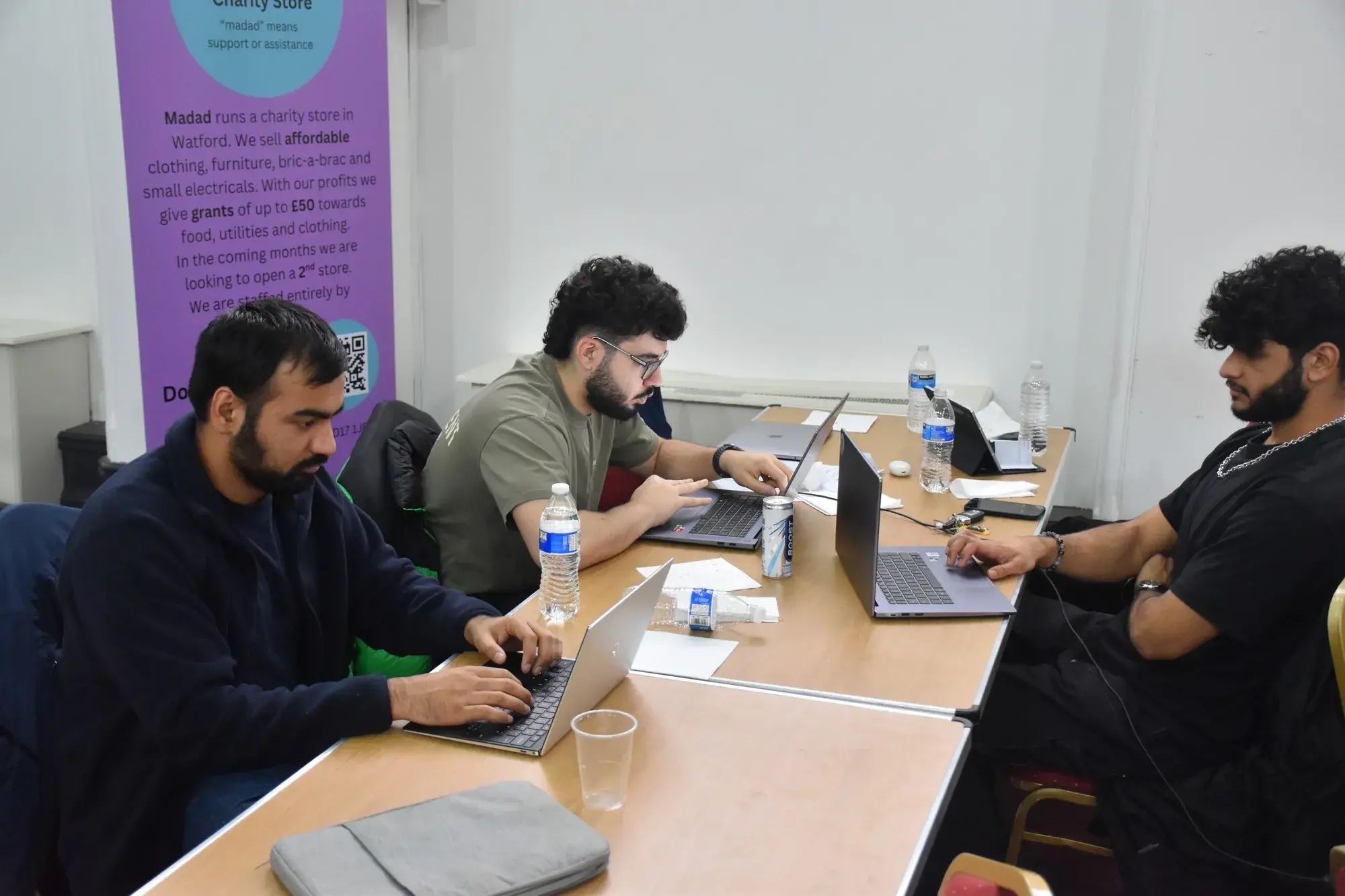 Participants coding beside a partner organisation banner