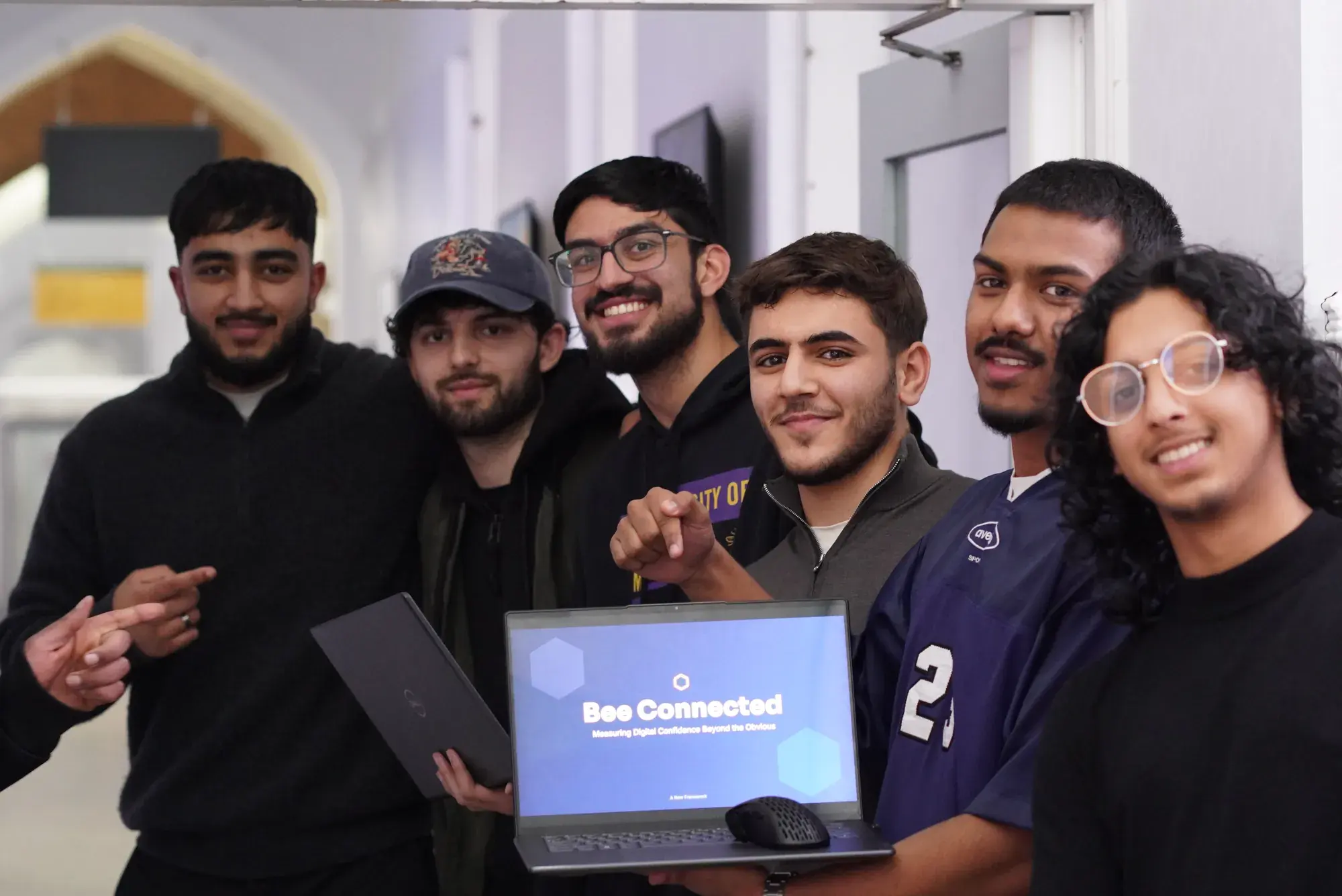 A hackathon team smiling beside their project on a laptop
